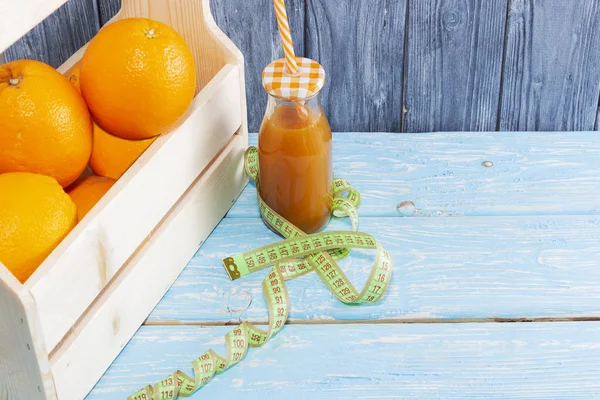 オレンジとジュースのボトルがたくさんあり 木のテクスチャの背景にテープを測定しています フィットネス スポーツ栄養 — ストック写真