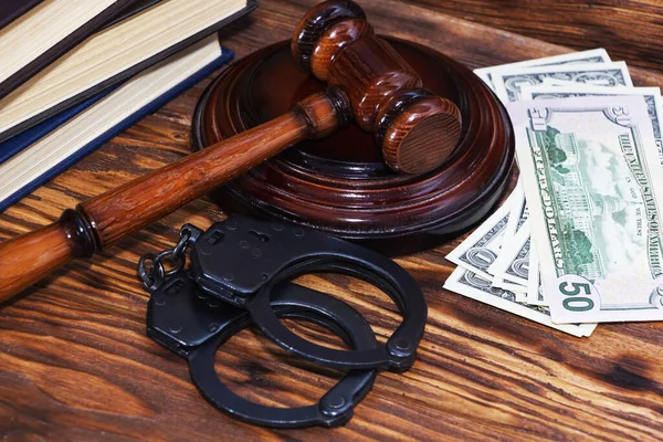 Handcuffs and a wooden gavel in front of manila folders