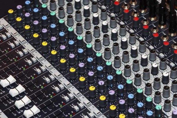Detail of a music mixer desk with various knobs.