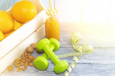 Bir sürü portakal, dambıl, ahşap desenli arka planda mezura. Fitness, spor beslenme