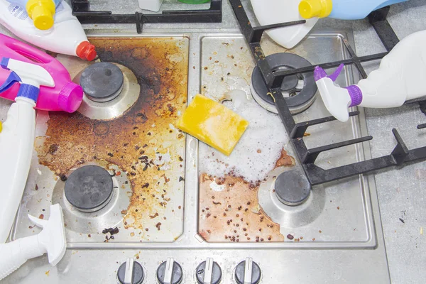 Smutsig kök spis, tomma och hela flaskor tvättmedel runt. — Stockfoto