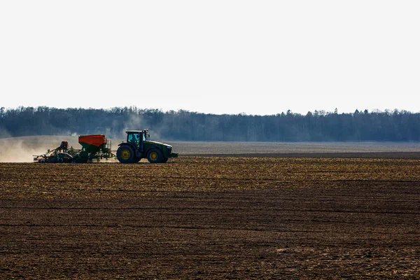 Ein großer Traktor mit Sämaschine fährt durchs Feld. — Stockfoto
