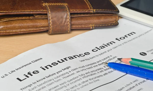 Life insurance claim form on a wooden surface — Stock Photo, Image