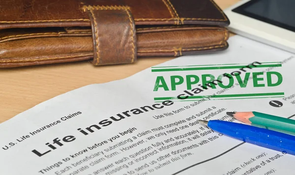 Life insurance claim form on a wooden surface — Stock Photo, Image