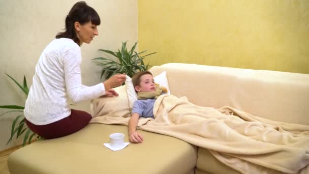 Niño enfermo, acostado en la cama, madre dándole medicina — Vídeo de stock