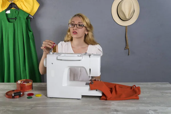 Girl sews colored dresses on  sewing machine — Stock Photo, Image