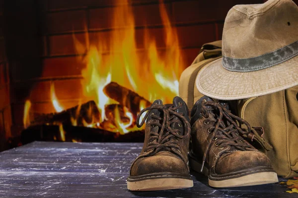 traveler\'s hat, bag and boots on a background of a burning fireplace