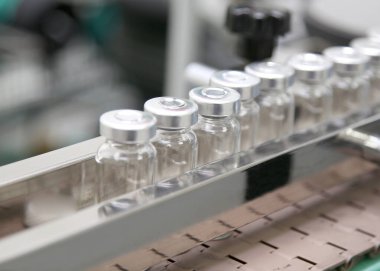 Fabrikada cam ampuller ve ilaçlarla üretim hattı. İlaç sanayisi. Virüs için tedavilerin geliştirilmesi