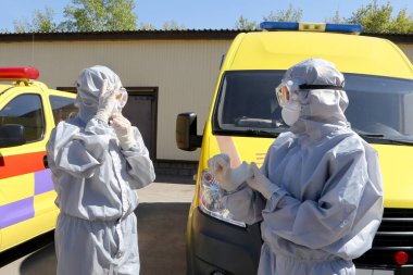 Ambulans uzmanları insanların enfeksiyon kaptığı yerlere gitmek için koruyucu giysiler giydiler. Koronavirüs enfeksiyonu için tedavi.