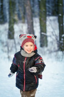Güzel karlı bir kış ormanında gülen çocuk