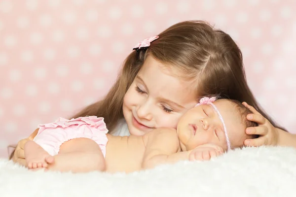 Cute little girl with a sleeping newborn sister — Stock Photo, Image