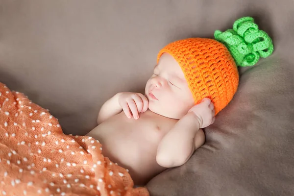 Bebé recién nacido con una zanahoria o un sombrero de calabaza de punto — Foto de Stock