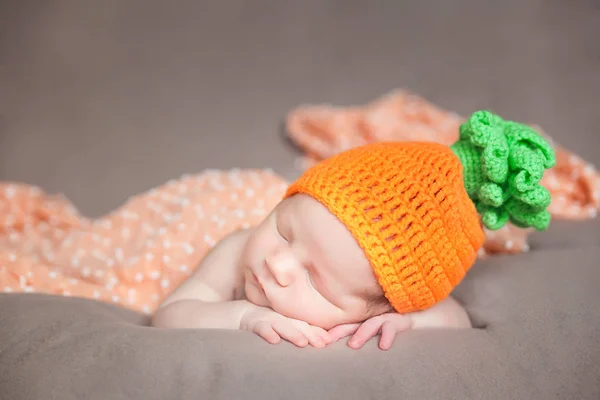 Yeni doğan bebek örme havuç veya kabak şapka giyiyor