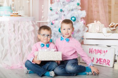 Noel süslemeli bir stüdyoda pastel renklerde iki kardeş.