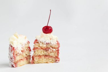 Krem şantili, kirazlı ve beyaz arka planda hindistan cevizli kekler.