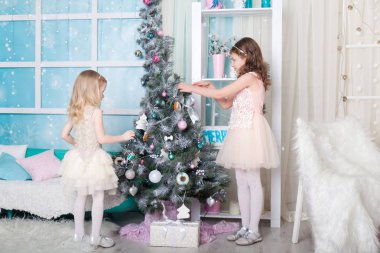 Noel süslemeli bir stüdyoda pastel renklerde iki kız kardeş.