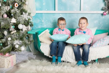 Noel süslemeli bir stüdyoda pastel renklerde iki kardeş.