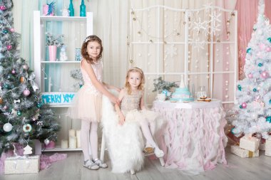 Noel süslemeli bir stüdyoda pastel renklerde iki kız kardeş.