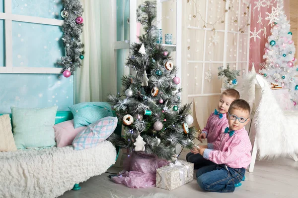 Noel süslemeli bir stüdyoda pastel renklerde iki kardeş.