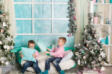 Noel süslemeli bir stüdyoda pastel renklerde iki kardeş.