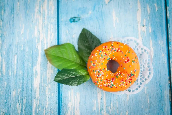 Donut doce laranja com folhas de flor verde — Fotografia de Stock