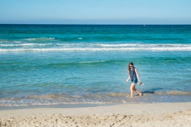 Sahilde yürüyüş güneş gözlüklü genç kadın