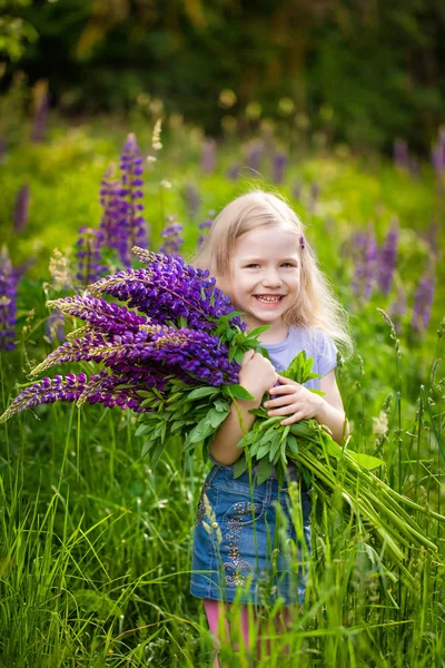 Niedliches Mädchen mit einem Strauß lila Lupinenblüten — Stockfoto