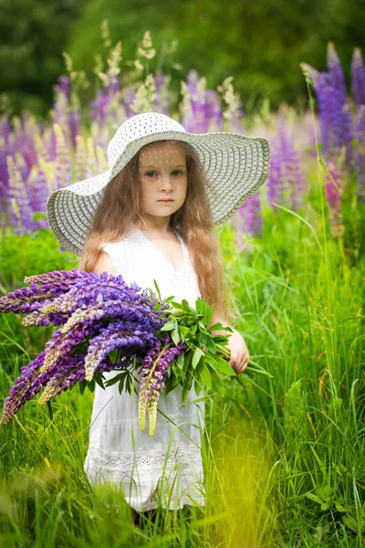 Linda chica con un ramo de flores de altramuz púrpura — Foto de Stock