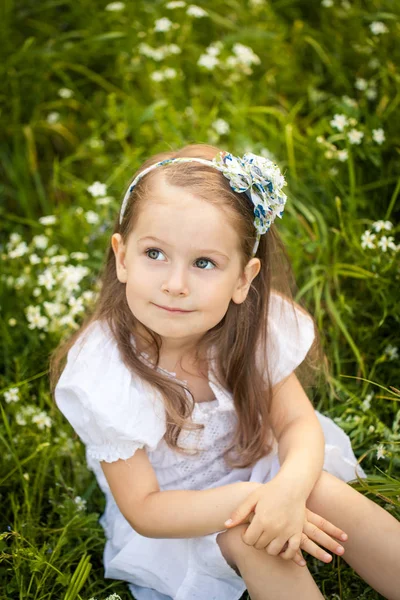 Kleines Mädchen in einem Feld mit weißen Blumen — Stockfoto