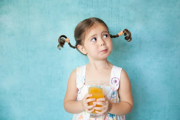 Улыбающаяся девушка со смешными косичками и стаканом сока — стоковое фото