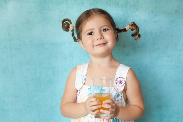 Usměvavá dívka s legrační copánky s sklenici šťávy — Stock fotografie