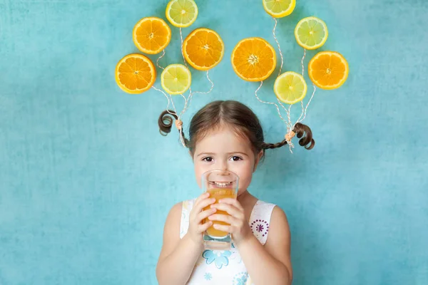 Smiling girl drinks fresh orange juice