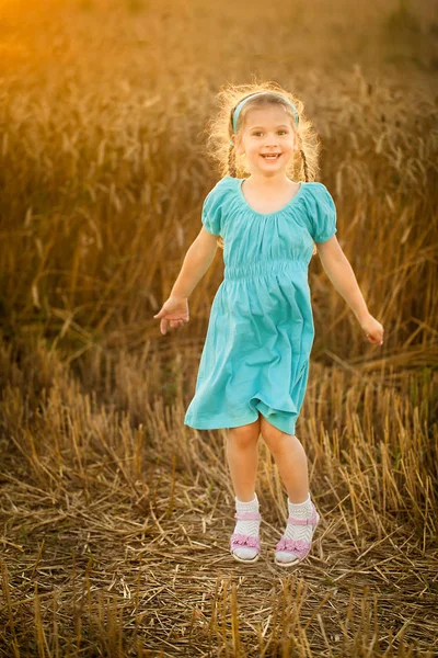 Счастливая девочка в пшеничном поле теплым и солнечным летним вечером — стоковое фото