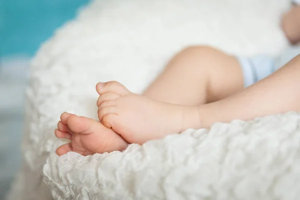 Niedliche Kinderbeine auf weißer Decke — Stockfoto