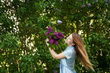 Üzerinde leylak çiçekleri olan mavi yaz elbisesi içinde güzel bir kadın.