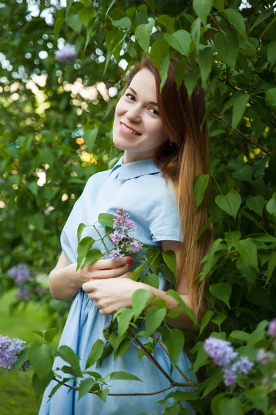 Hermosa mujer en un vestido de verano azul con flores lila en una b — Foto de Stock