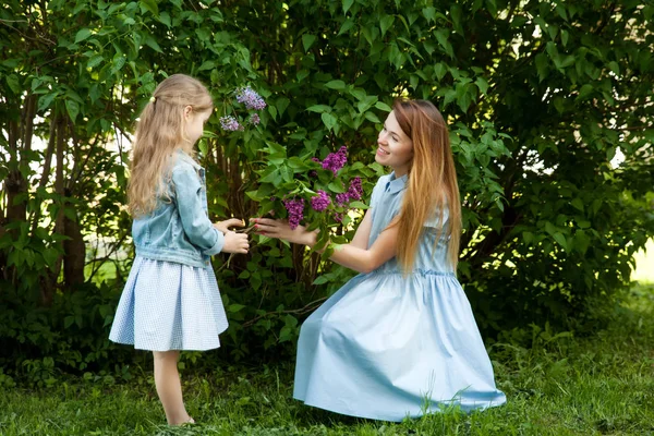 Güzel gülümseyen genç bir anne ve buketi olan sevimli bir kız. — Stok fotoğraf