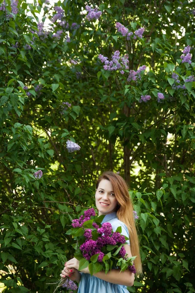 Beautiful woman in a blue summer dress with lilac flowers in a b — Stock Photo, Image