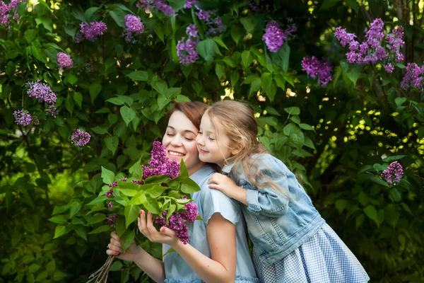 Gyönyörű mosolygós fiatal anya és aranyos lánya egy csokor — Stock Fotó