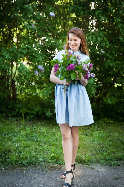 Hermosa mujer en un vestido azul de verano con flores lila en un jardín floreciente. Flor de primavera . — Foto de Stock