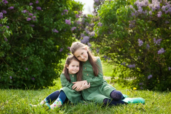 Yeşil Keten Elbiseli Iki Kız Kardeş Parkta Çiçek Açan Leylaklarla — Stok fotoğraf