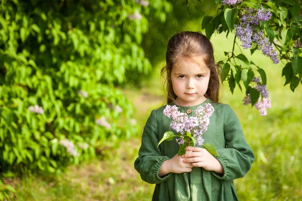 Yeşil Keten Elbiseli Tatlı Kız Parkta Çiçek Açan Leylaklarla Eğleniyor — Stok fotoğraf