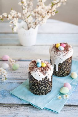 Paskalya pastası kulich. Geleneksel Paskalya tatlı ekmeği şeker jöleli ve şeker kamışlı yumurta ve çikolata parçacıklarıyla süslenmiş. Arka planda Paskalya Ortodoks pastası ve kiraz çiçeği dalı