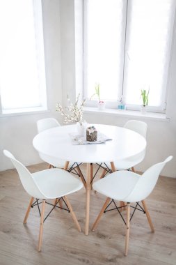 Bahar çiçekli kiraz dallarıyla Paskalya masası ve hafif bir nisan mutfağında Paskalya pastası, modern iç mekan.