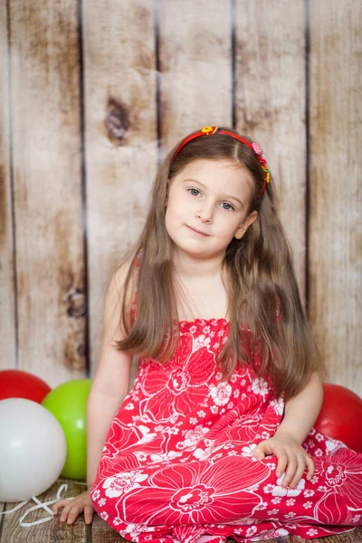 笑顔若いです女の子で赤いドレスで木の背景にあります遊びますとともに風船 — ストック写真