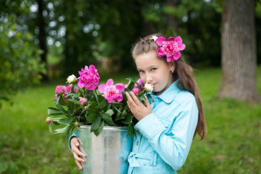 Turkuaz kot ceketli, üzerinde büyük şakayık desenli metal kovası olan güzel esmer kız.