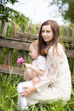 Güzel genç bir kadın ve oğlu eski ahşap çitlerin yanında.