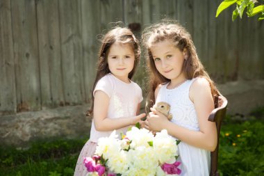 Yaz bahçesinde sevimli bir tavşanla mutlu kız kardeşlerin portresi. Paskalya konsepti