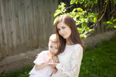 Mutlu anne ve oğlunun yaz bahçesinde sevimli bir tavşanla oynadığı portre. Paskalya konsepti