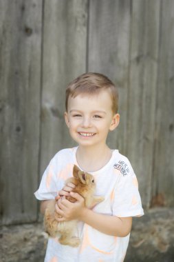 Bir yaz bahçesinde sevimli bir tavşanla mutlu bir çocuğun portresi. Paskalya konsepti